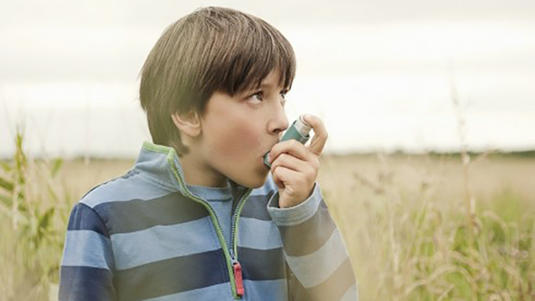 Boy using inhaler outdoors in a field