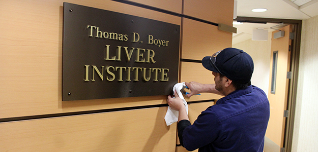 UA Facilities' Adam Jacobs tightens the final screw on new Liver Institute signage