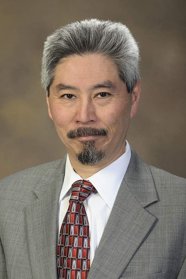 [Head-and-shoulders photo of older Asian-American man with salt-and-pepper gray hair, a goatee, wearing a grayish blazer, white dress shirt and red-and-gray tie]
