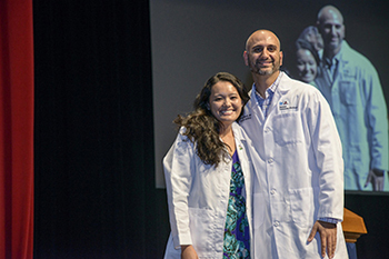 Dr. Raed Sukerji assists a student in putting on first white coat