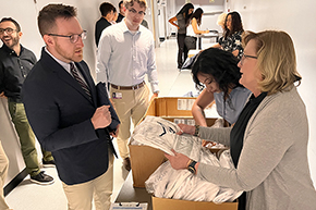[Residency program manager Mary Gosciminski hands out personalized white coats to physicians.]