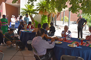 [Dr. Francisco Moreno, associate vice president of the UAHS Office of Equity, Diversity & Inclusion, addresses the crowd at the UAHS Hispanic Heritage Month Celebration, as Ted Tong, PharmD (center foreground), listens.]