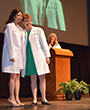 [Dr. Janet Campion and student have photo taken after Dr. Campion presents student with first white coat of career.]