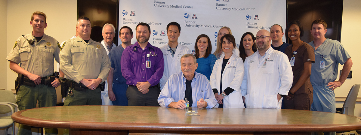 [Robert Freel pictured with first responders and members of medical team that resuscitated him. (Photo credit: David Mogollon, UA Department of Medicine)]
