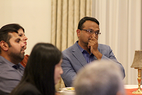 [Close-up of South Asian man with his hand over his chin as colleagues look on from the left at ceremony at the Arizona Inn]