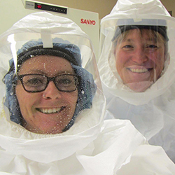 [A student and Bridget Marie Barker, PhD, suited up and working in her lab]