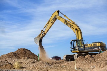 [An excavator dumps dirt at a construction site]