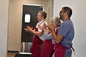 From foreground backwards, Kanwal Bains, MD, CNSC, Mindy Fain, MD, and David Lieberman, MD, clap as Dr. Juanita Merchant (offstage left) thanks Hacienda at the River executive chef David Sullivan and membership director Lisa Terry-Jones for hosting the Docs in the Kitchen cooking demonstration and fundraiser for the UArizona Division of Gastroenterology.
