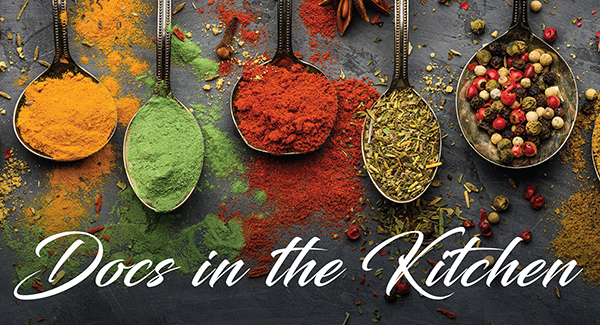 Image of spoons with various spices in yellow, orange, green, red... with "Docs in the Kitchen" overlayed on it
