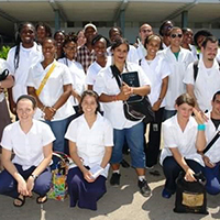 Dr. Bailey (2nd row, left) in medical school at Cuba’s ELAM with classmates and actor Danny Glover (middle in plaid shirt and hat) who was visiting to learn more about health, social justice and universal health care