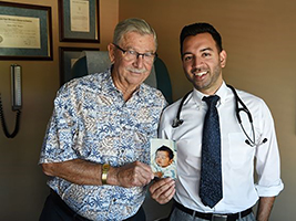 Dr. Rishi Bhargava with cardiology patient and the doctor at his birth, Alan Spear, MD (retired), holding a photo of Dr. Bhargava as a newborn.