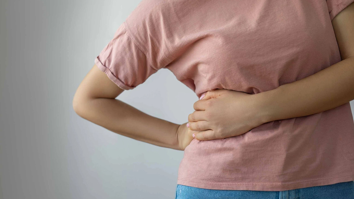 [Image of a woman holds her side as if in pain, illustrating a paper with published results on a clinical trial led by University of Arizona Health Sciences researchers found that a three-drug chemotherapy treatment for advanced stage, inoperable biliary tract cancers didn’t improve patient survival when compared with the standard two-drug treatment. (Photo by Bymuratdeniz via Getty) ]