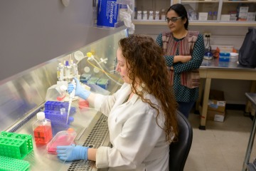 [Dr. Lalitha Madhavan (right) oversees a lab whose discoveries in skin cells could help scientists take a closer look at brain cells.]