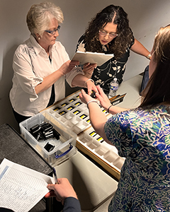[Residency program staff Julie Forte (left) and Monica Jimenez check over the pager numbers to make sure physicians get the right pagers.]