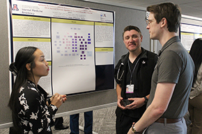 [Chief Resident Kevin J. Moynahan, MD (right), discusses research behind the poster — "Optimizing Treatment of Diabetic Ketoacidosis (DKA) to Improve Outcomes with Education and an Improved Treatment Algorithm for Use with In-House DKA Order-Set" — of IM resident Allysha Yasuda, MD (left), while IM resident William Waidelich, MD, listens in.]