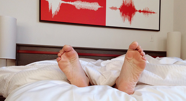Bare feet of sleeper in bed with heart rhythm  painting above headboard [Max Pixel]