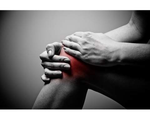 [Black-and-white image of man holding knee with redness around knee as if in pain]