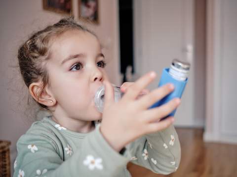 [Young child using inhaler with a spacer device.]