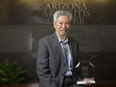 [Portrait of a man standing in a suit in front of the Arizona Arthritis Center sign.]