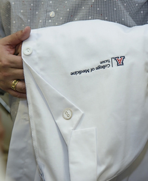 UA College of Medicine Tucson student with white coat over his arm