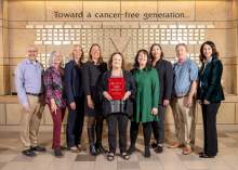 [Cancer Center members stand with Heather Alberts (center with plaque honoring Dr. David Alberts, MD’s many contributions to the center and cancer research) and their daughter, Sabrina Plattner (at right of Alberts). Also pictured are the Department of Medicine’s Jennifer Bea, PhD (third from right), co-leader of the Cancer Prevention and Control Program, and Clara Curiel-Lewandrowski, MD (far right), the center’s interim director of research, co-director of the Skin Cancer Institute and Dermatology divisi]