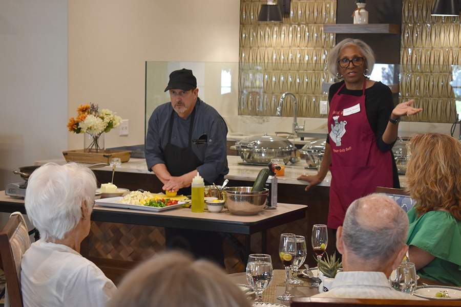 [Pictured here with Chef David Sullivan, Juanita Merchant, MD, PhD, talks to attendees at Docs in the Kitchen culinary demonstration for healthy eating at the Hacienda at the River retirement community in June 2023.]