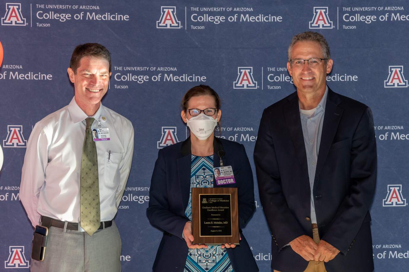 [Dr. Laura Meinke is presented with the Award for Excellence in Graduate Medical Education by Dr. Kevin Moynahan and Dr. Conrad Clemens.]