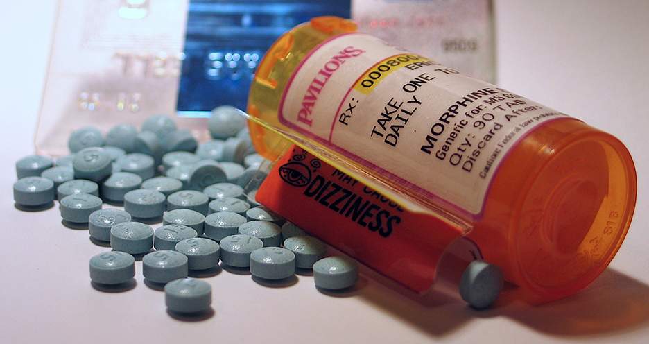 [Picture of orange prescription bottle of morphine pills with blue tablets scattered next to it]