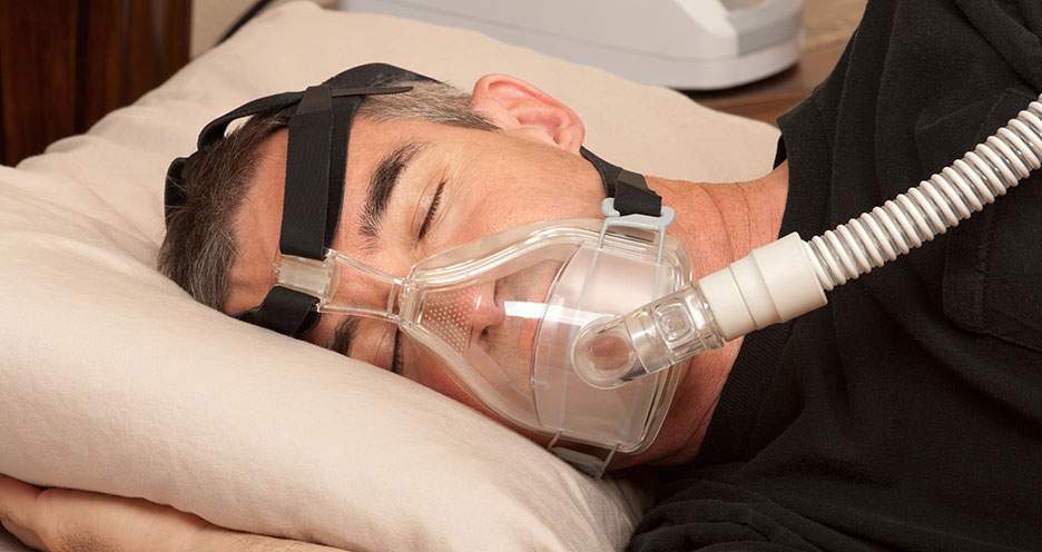 [Man in bed wearing CPAP device to assist his sleep]