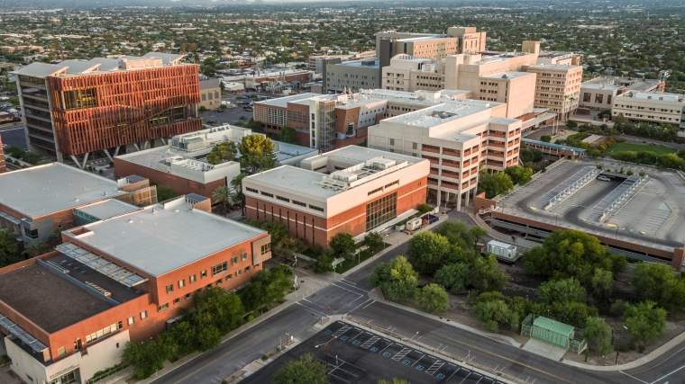 Pictured is an aerial photo of the University of Arizona Health Sciences campus in Tucson looking northwest from the parking lot east of the Mel and Enid Zuckerman College of Public Health and the College of Nursing with the Health Sciences Innovation Building upper left and Banner - University Medical Center Tucson upper right
