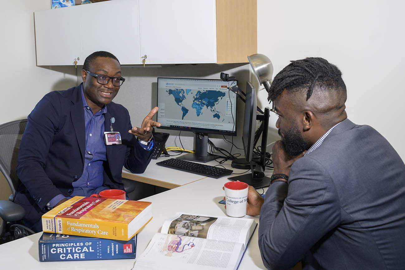 Christian Bime, MD, meets with Atehkeng Zinkeng, a medical student from Cameroon, in his office.