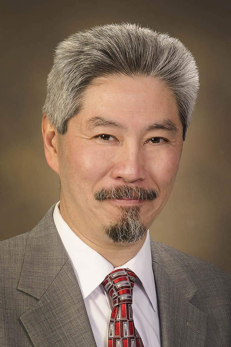 [Image of Asian man with goatee wearing red tie, white shirt and tan jacket]