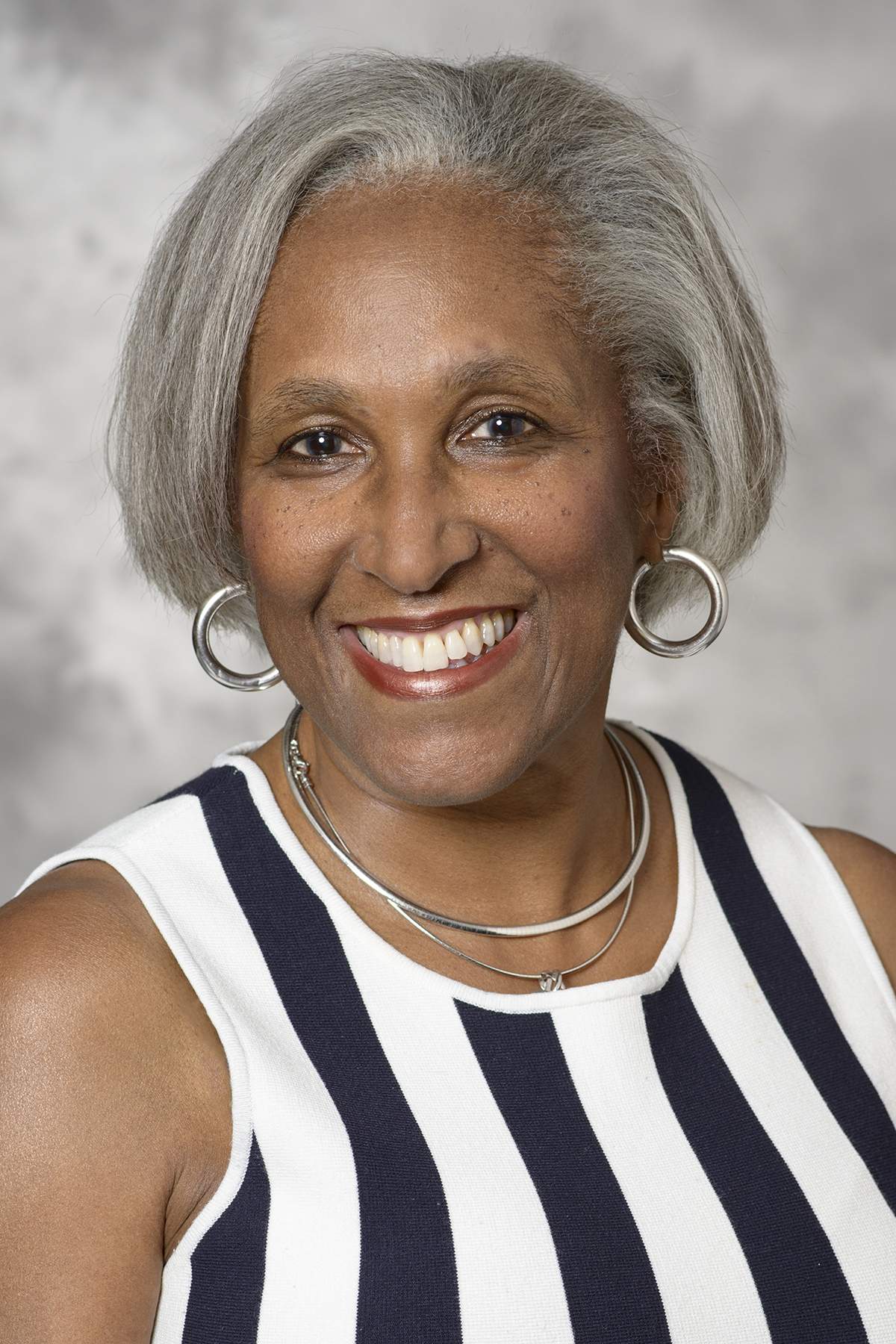 [Photo of a black woman with gray hair wearing a blue-and-white striped sleeveless blouse.]