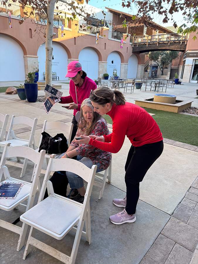 [Sarver Heart Center outreach manager Cara Deery helps a Sarver Stepper with her Strava app to track her fitness activities.]