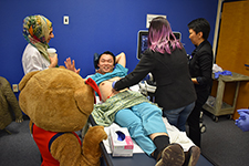 Wilma watches ultrasound of Dr. Wei Xiang Wong by high school student at health career fair